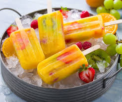 Polos helados de frutas sobre un bol con hielo para disfrutar del verano.